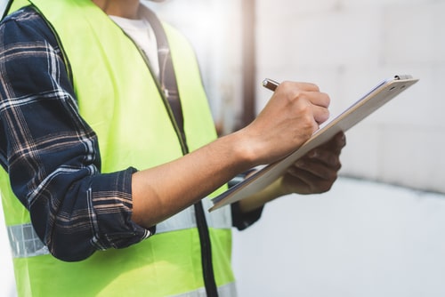 employee in vest holding check-list